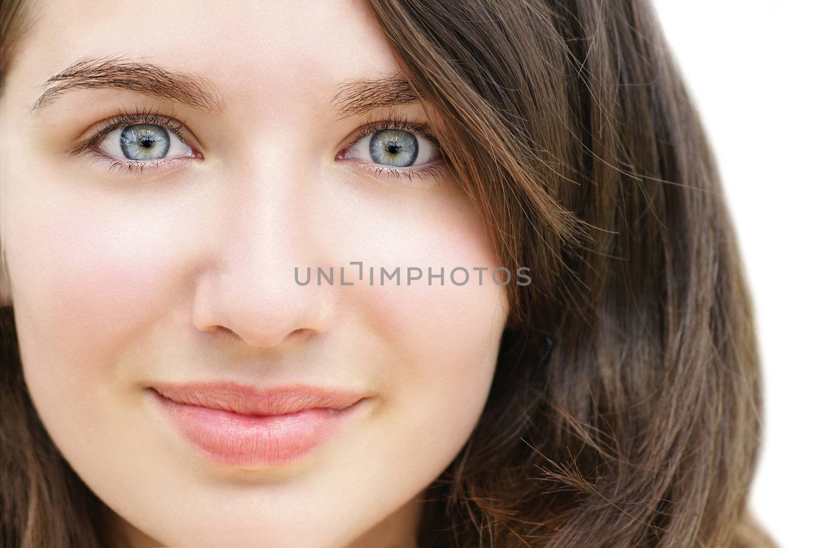Portrait of a beautiful young woman, teenager or student with stunning light blue eyes and fare skin, looking surprised with her wide eyes and little smile.
