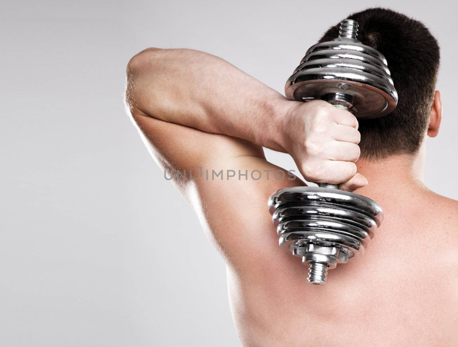 Athletic man lifting a dumbbell, studio photo