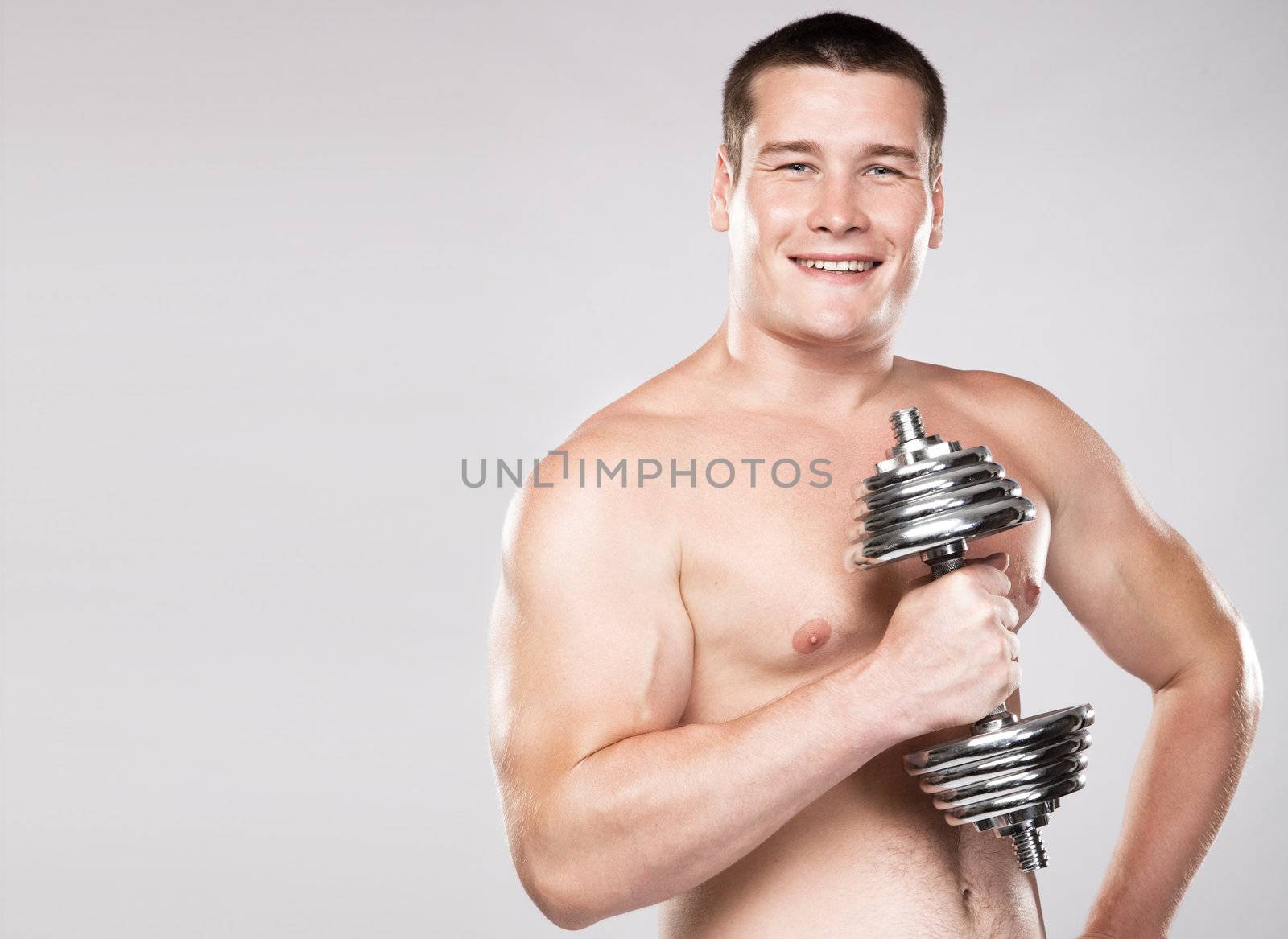 Athletic man lifting a dumbbell, studio photo