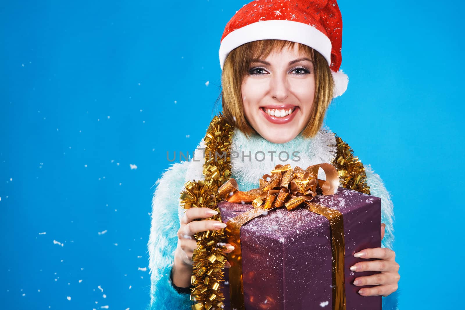 Festive girl with Christmas gift against blue background 