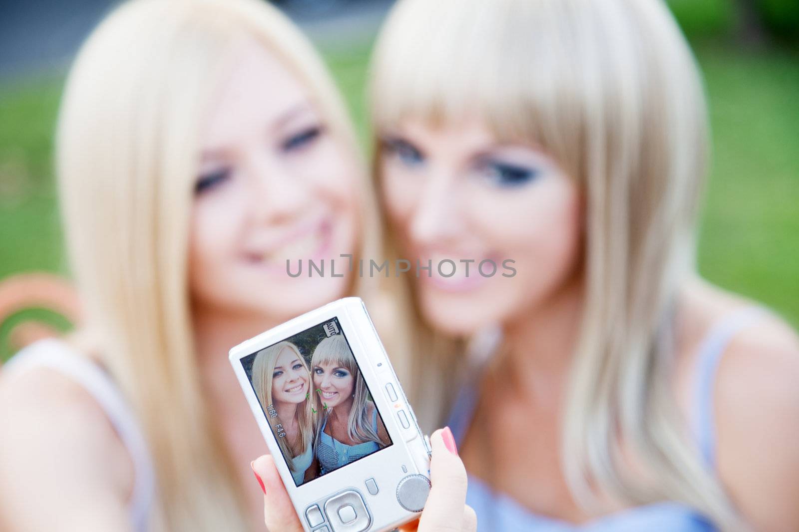 Two beautiful young girl friends with a digital photo camera