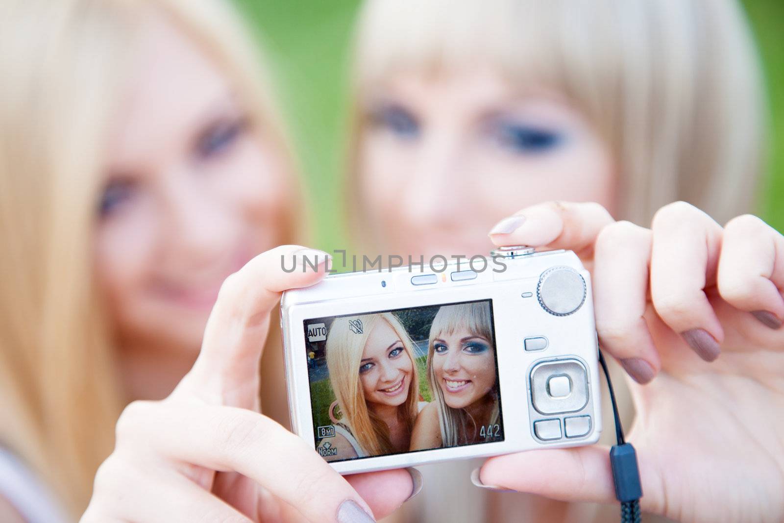 Two beautiful young girl friends with a digital photo camera