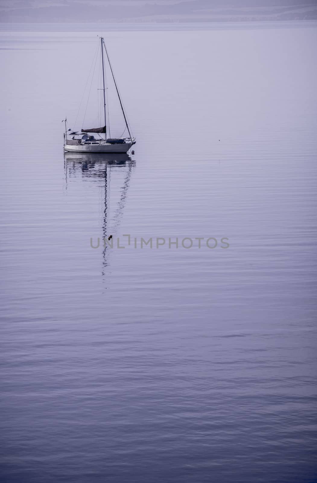 Lone yacht sitting moored in the beautiful still water at sunrise