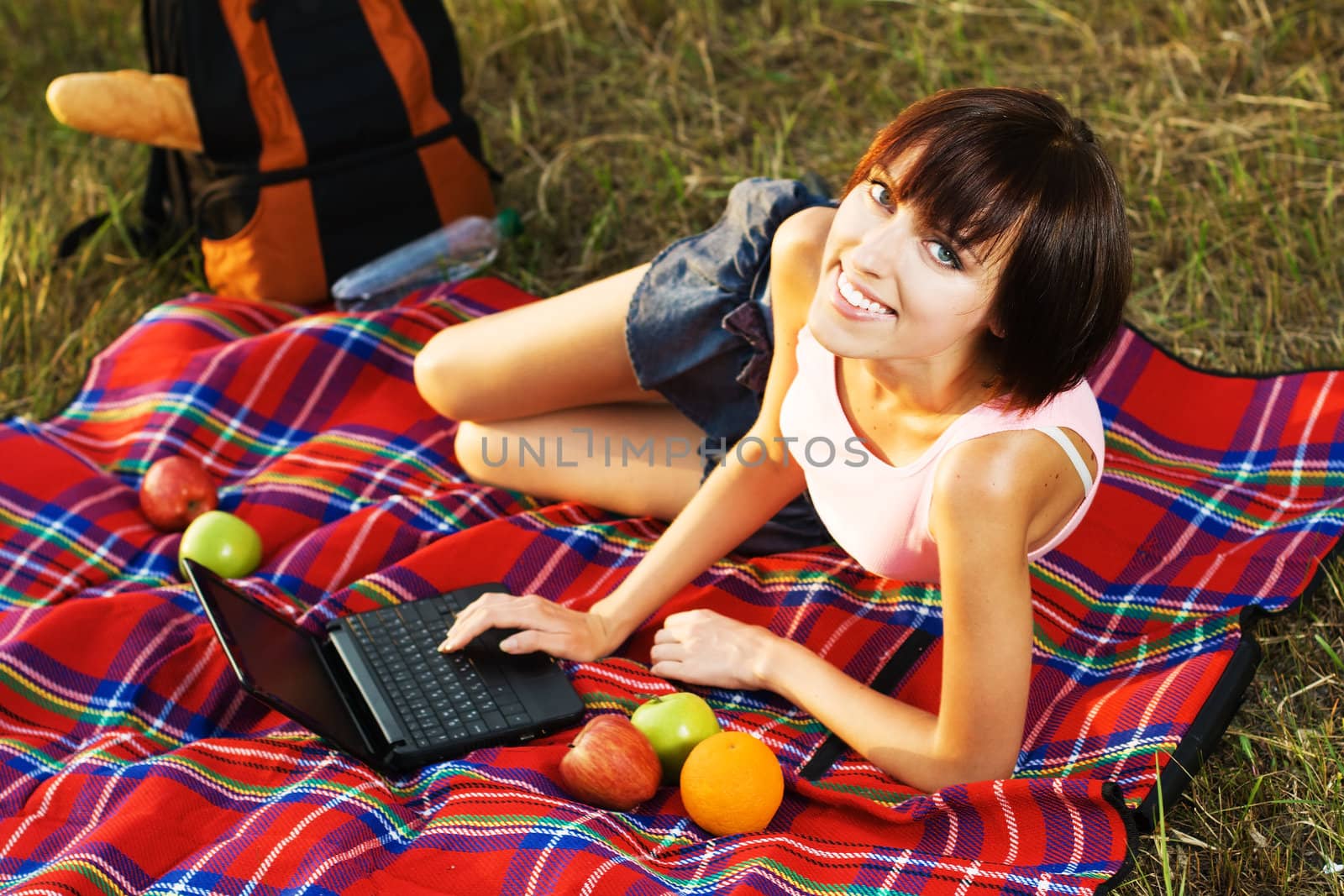 Lovely girl having a rest with laptop on picnic in the park 