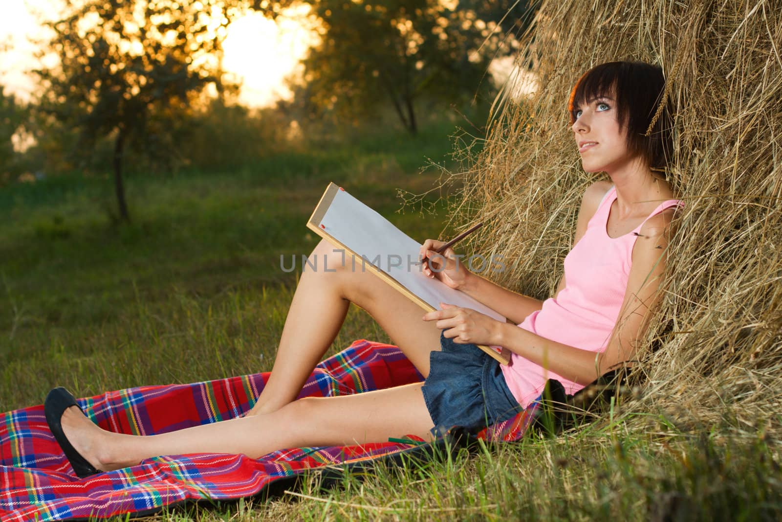 Lovely girl having rest and drawing in the park