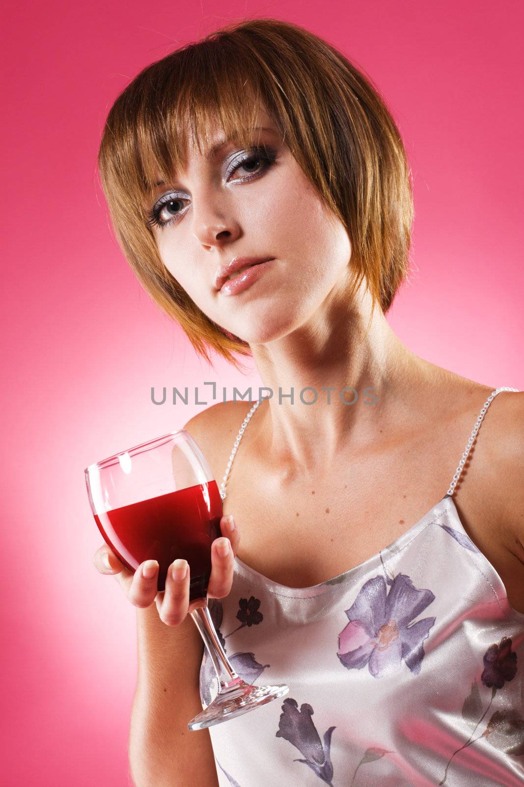 Portrait of a beautiful woman with a glass of wine against pink background