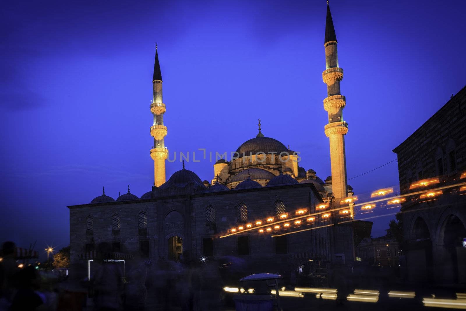 A mosque shot in the evening in Istanbul. Blured people seen in front of the mosque.