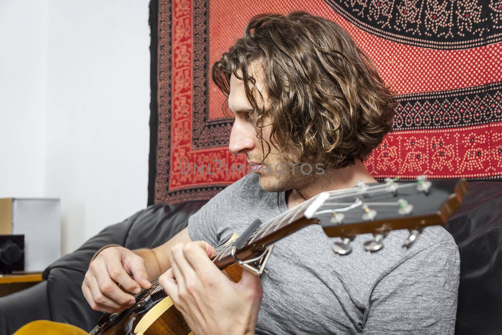 An image of a handsome guitar player with a curly hairdo
