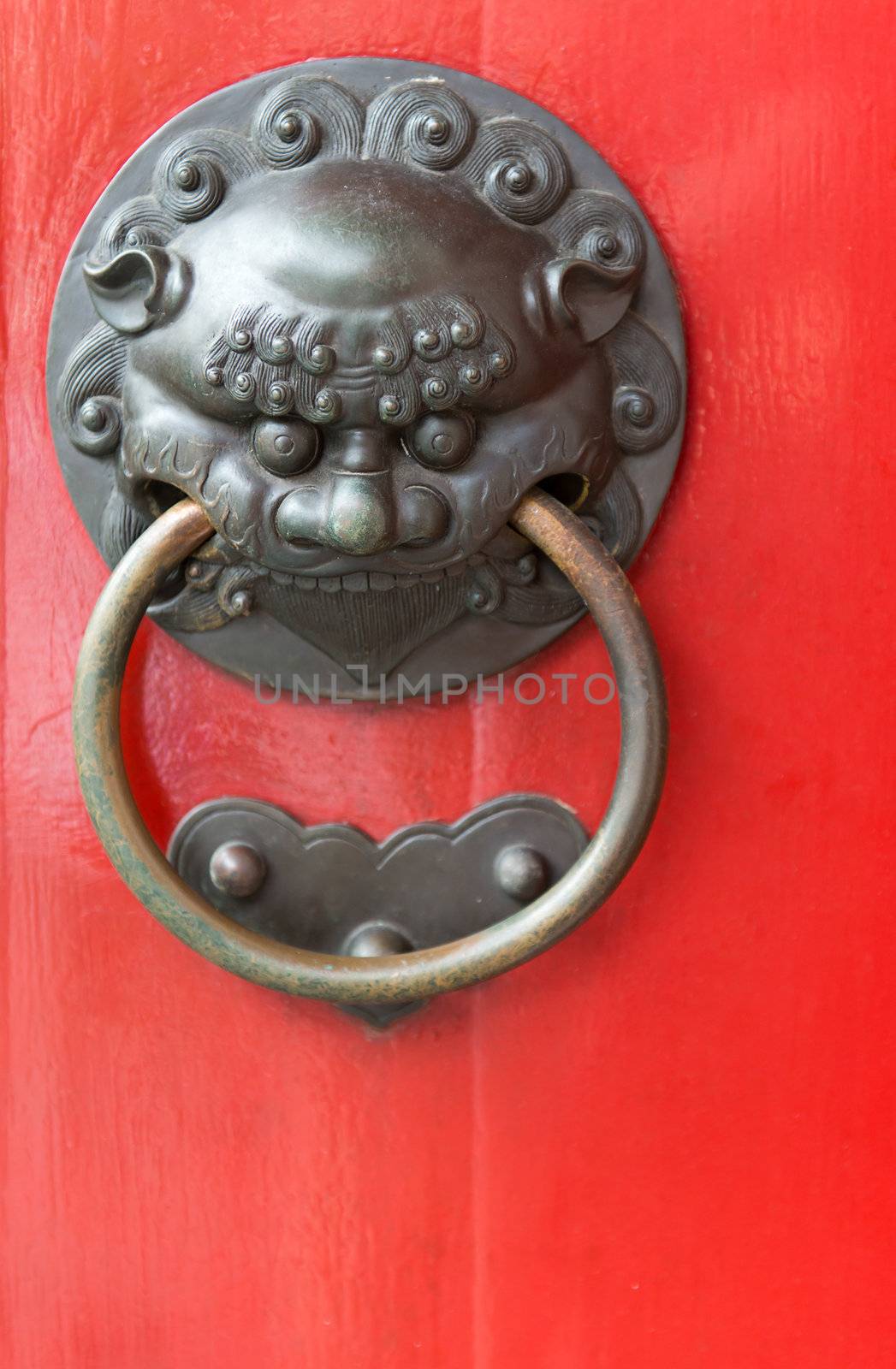 Old red chinese door with decorative metal handle, selective focus on the face front