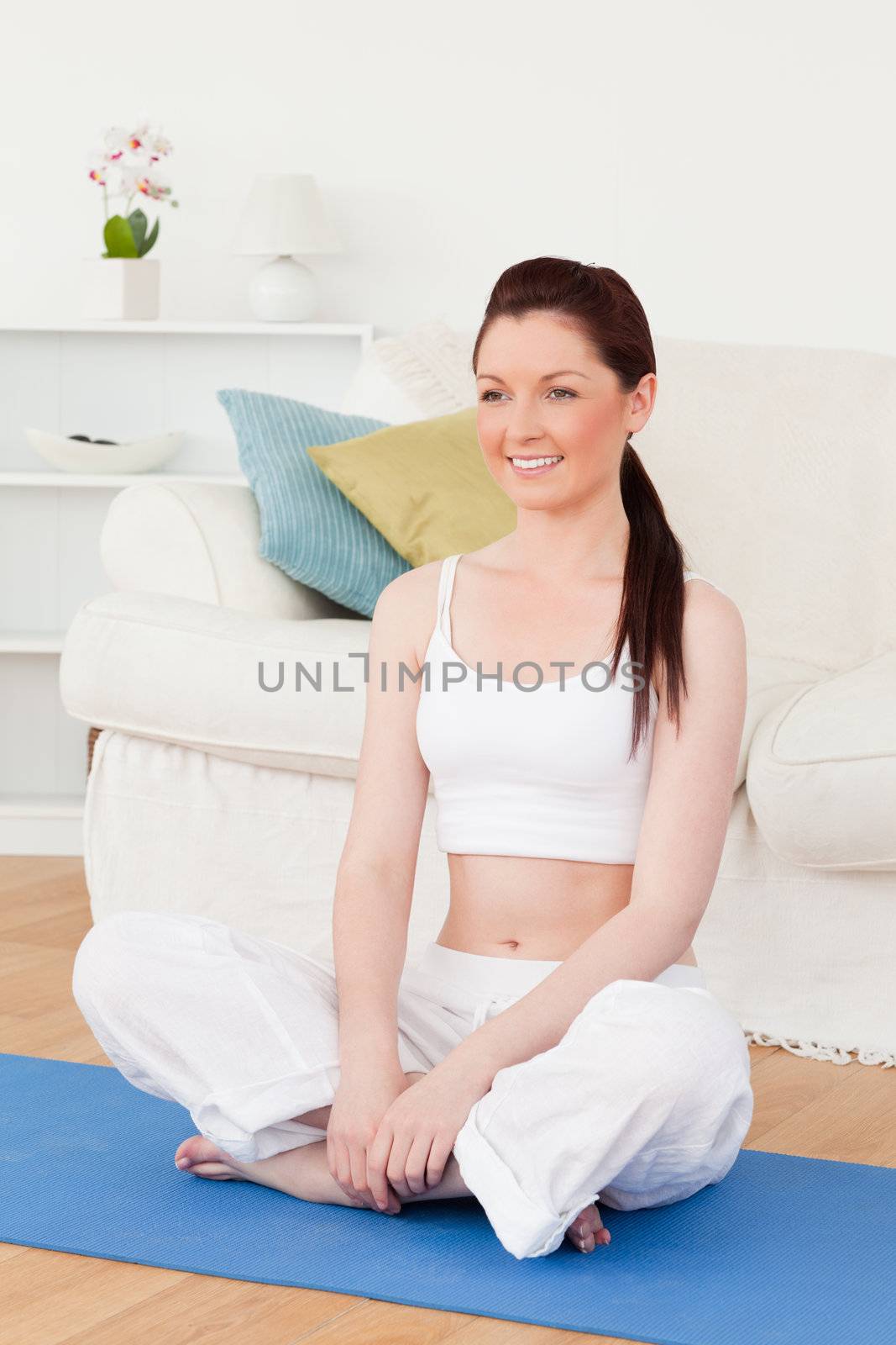 Beautiful woman posing while sitting on a gym carpet in the living room