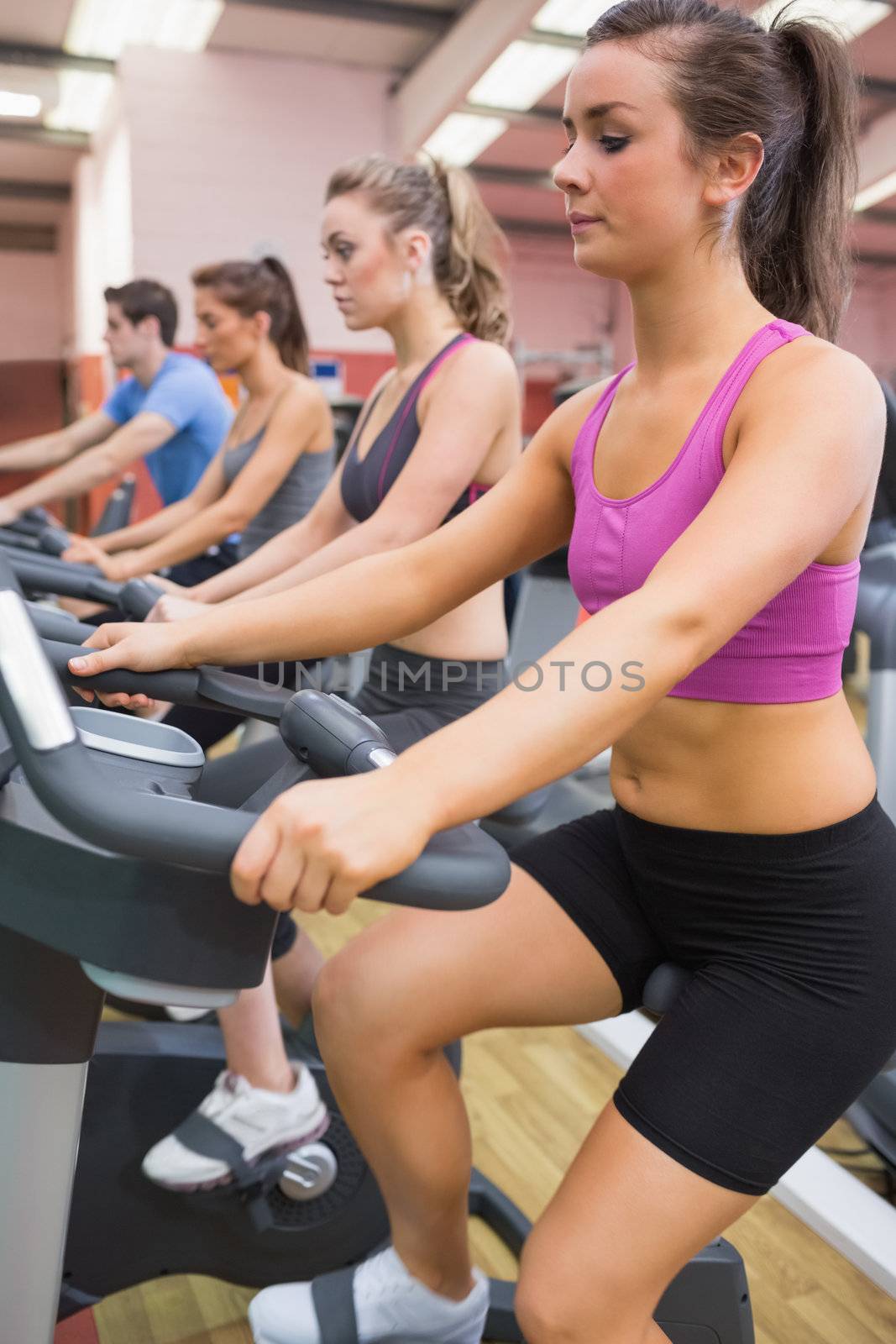Group of people on exercise bicycles by Wavebreakmedia