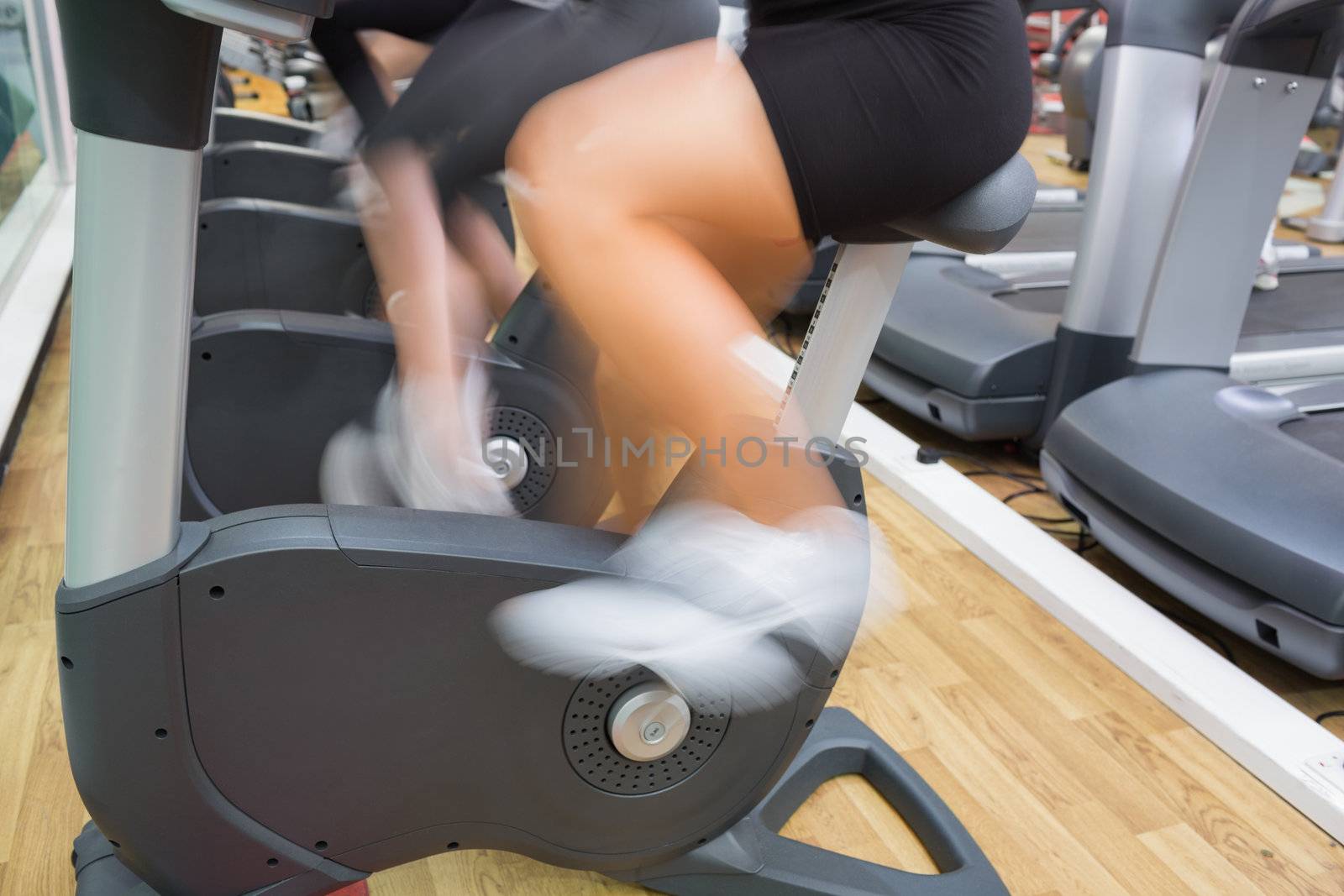Female legs on exercise bicycle in the gym
