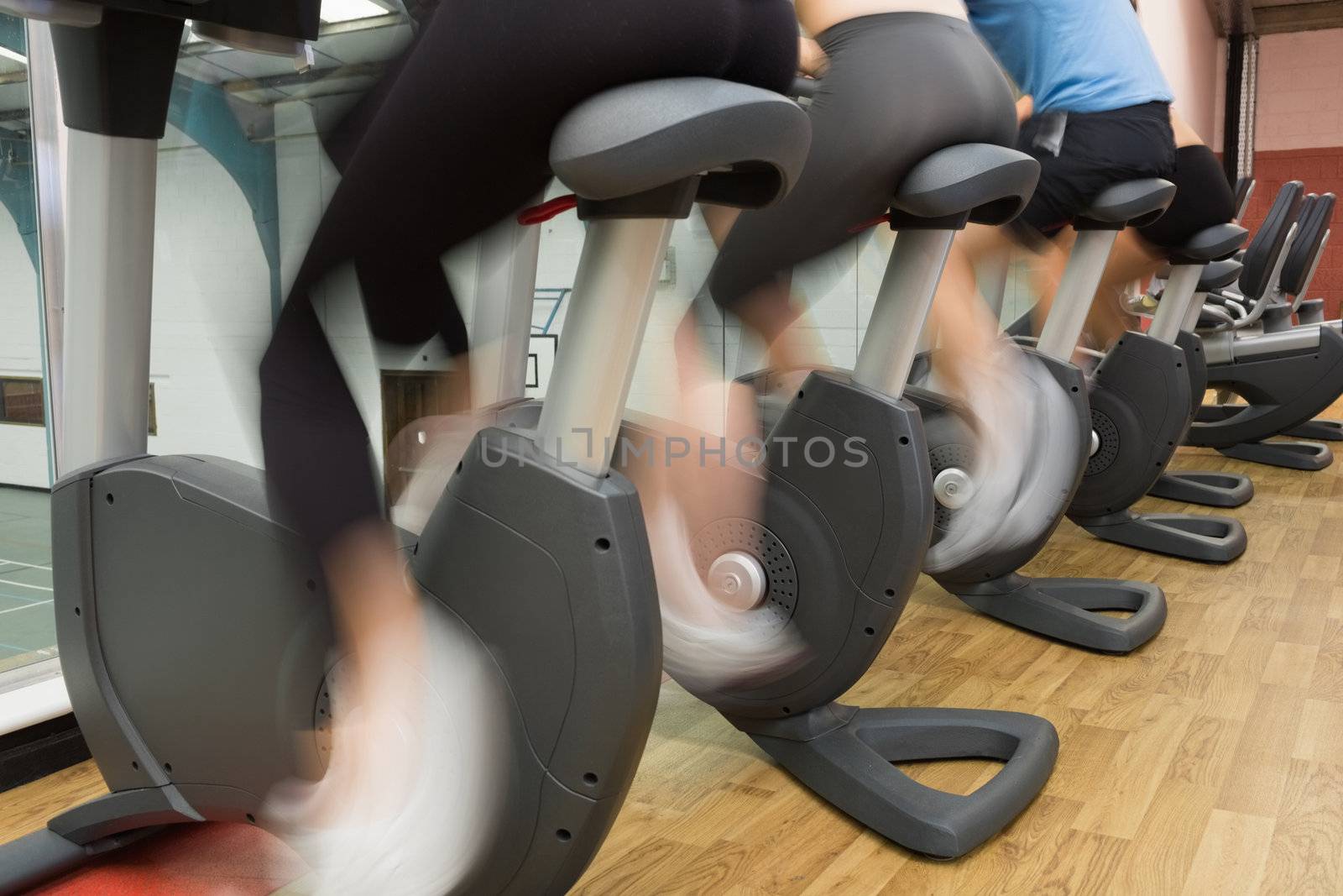 People riding on exercise bikse in gym