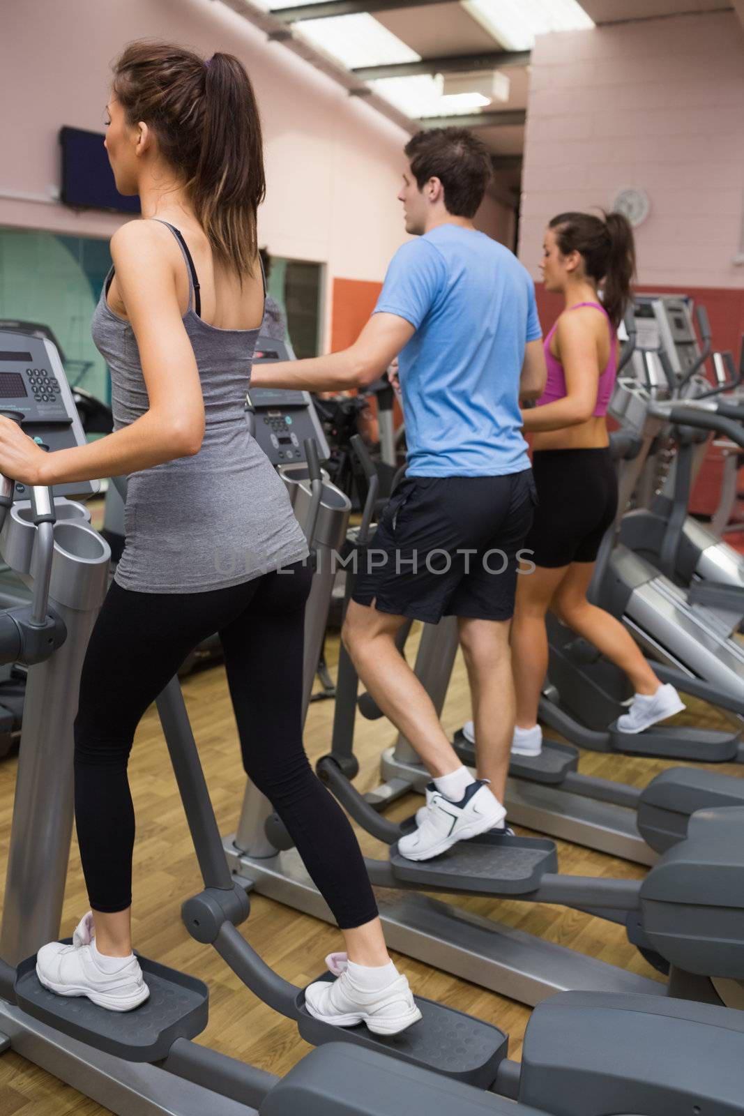 Three people training on  step machines in gym