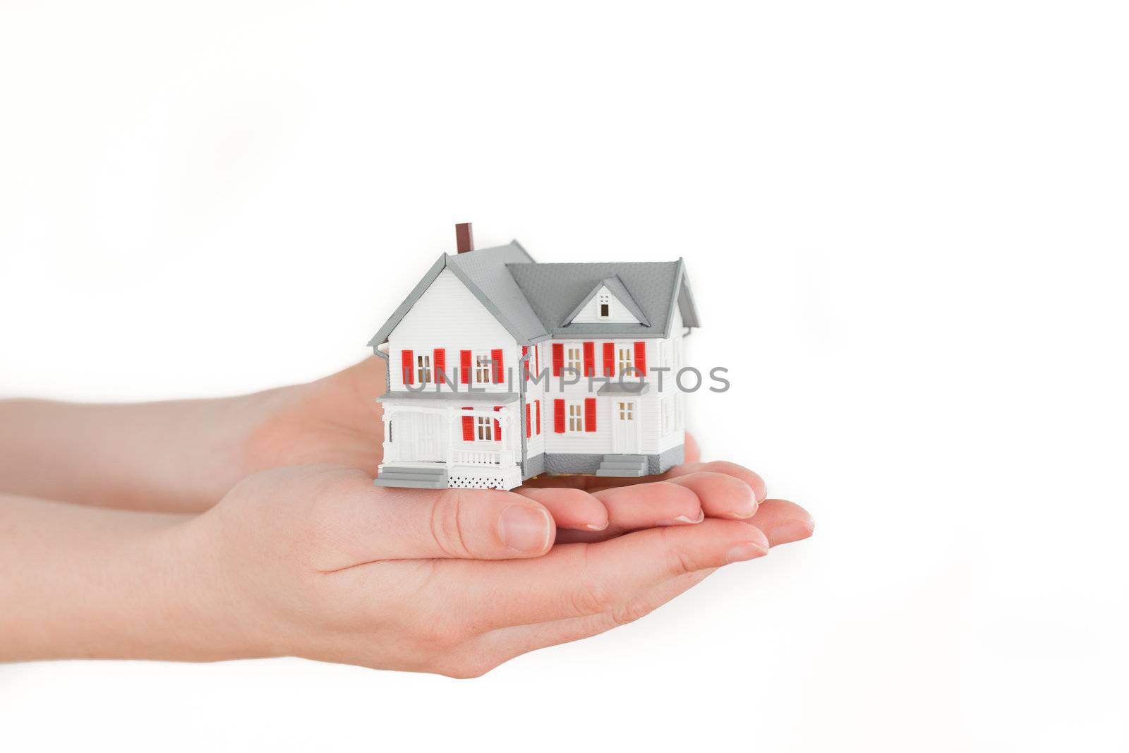 Hands holding a miniature house on a white background