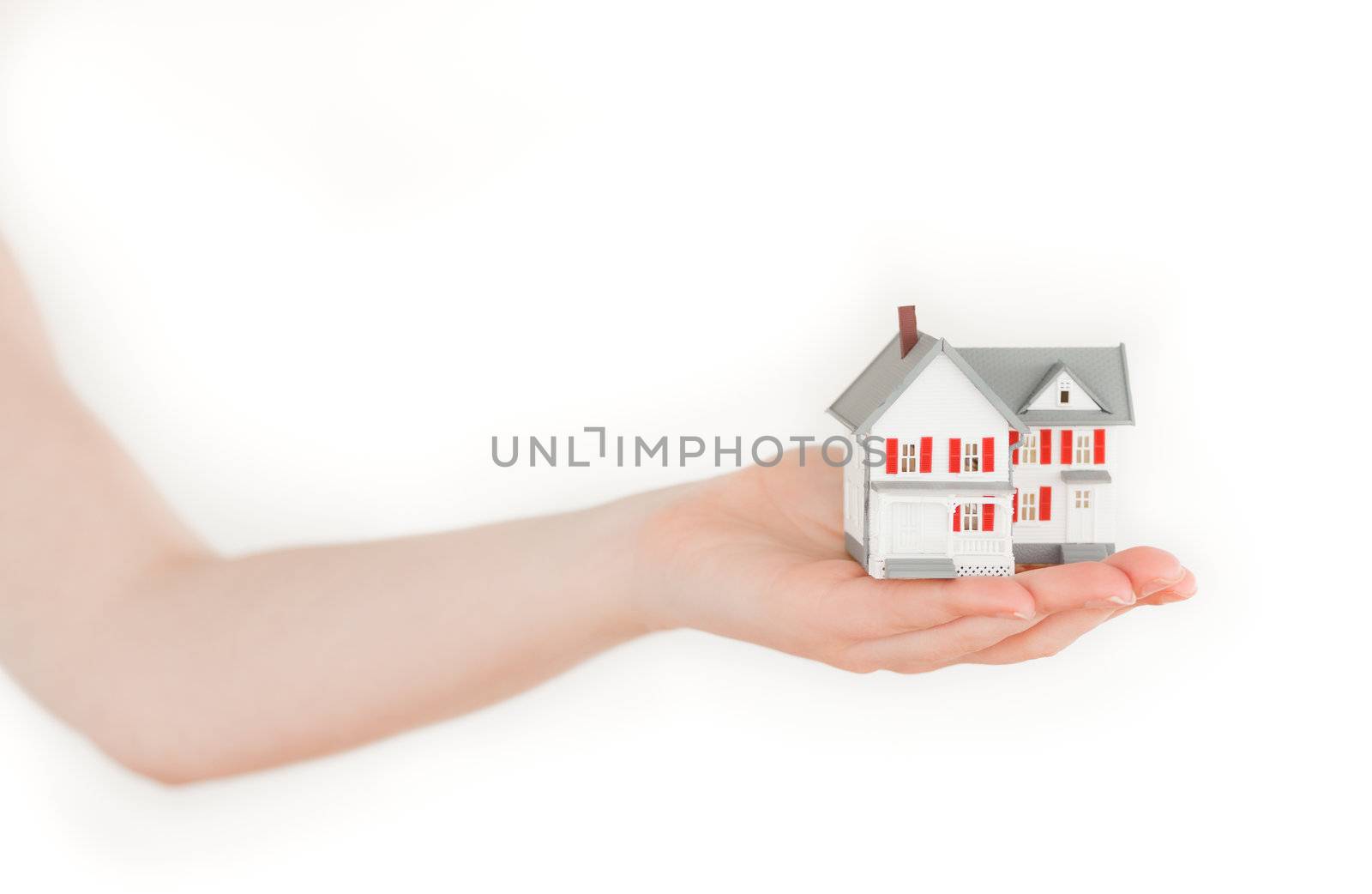 Arm holding a miniature house on a white background