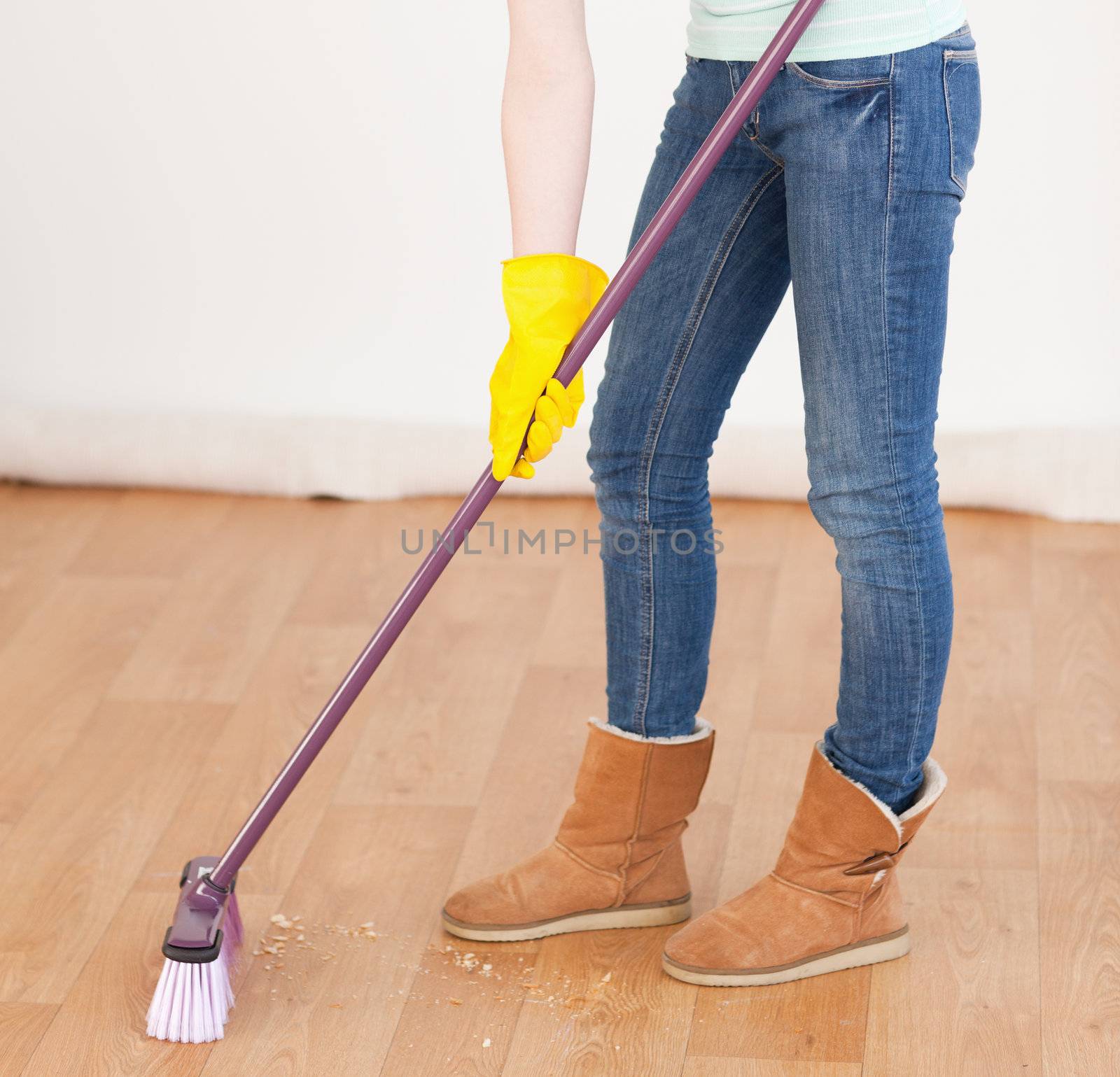 Attractive red-haired woman sweeping the floor at home