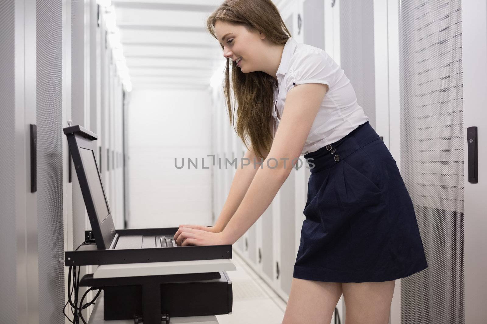 Woman doing maintenance on servers with a laptop in data center