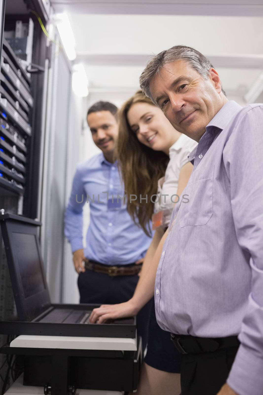 Three happy technicians checking servers with laptop by Wavebreakmedia