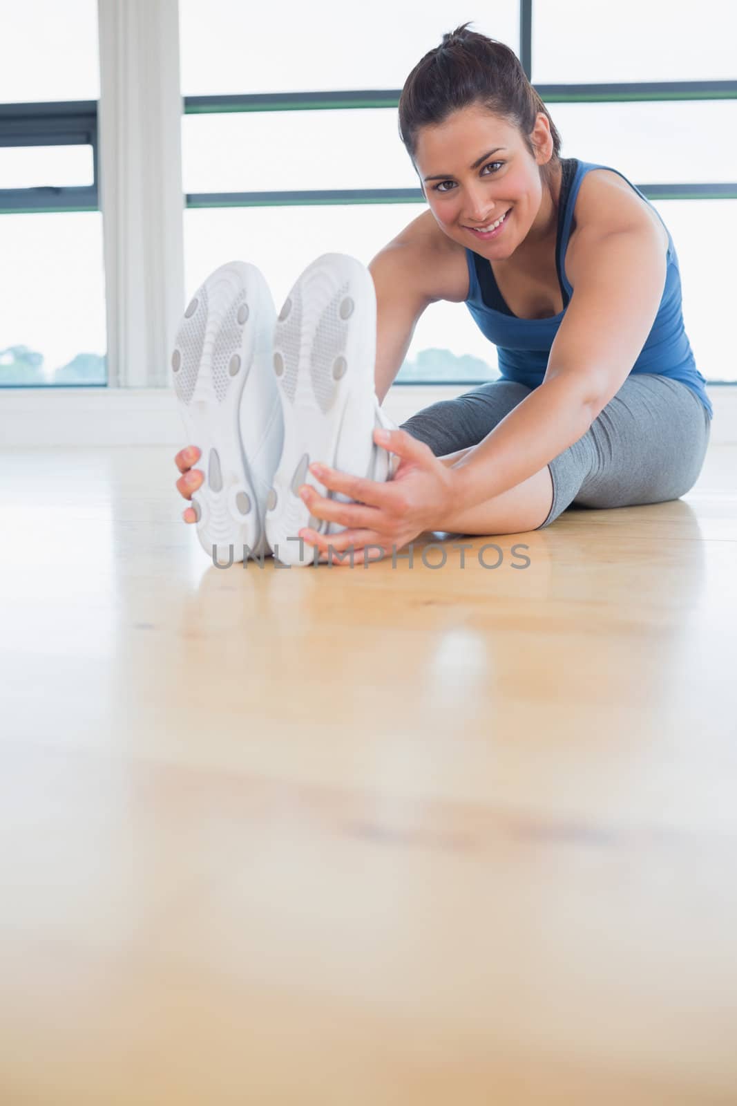 Happy woman stretching legs in fitness studio
