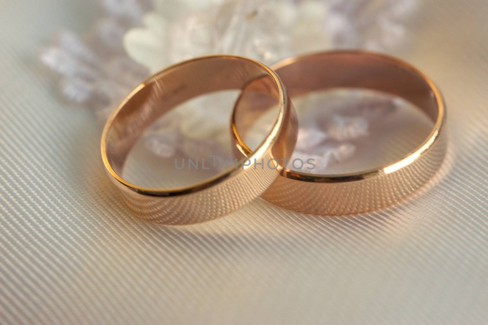 Two wedding rings lie on a white pillow