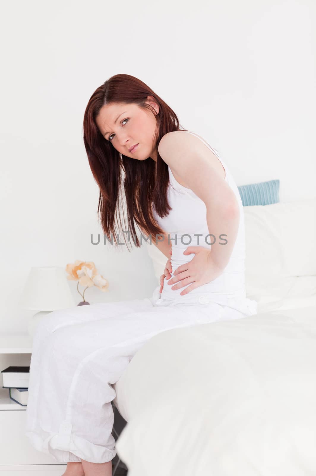 Attractive red-haired female posing while sitting on her bed by Wavebreakmedia