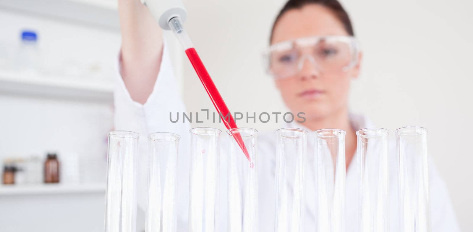 Beautiful red-haired scientist filling up a test tube in a lab