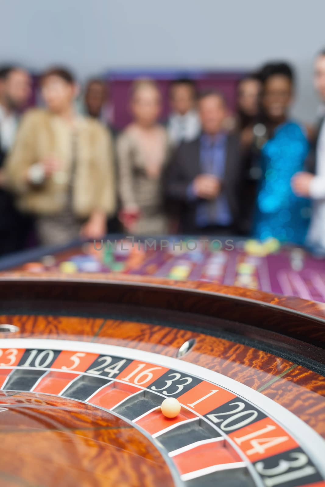 People standing looking at the roulette wheel at the casino