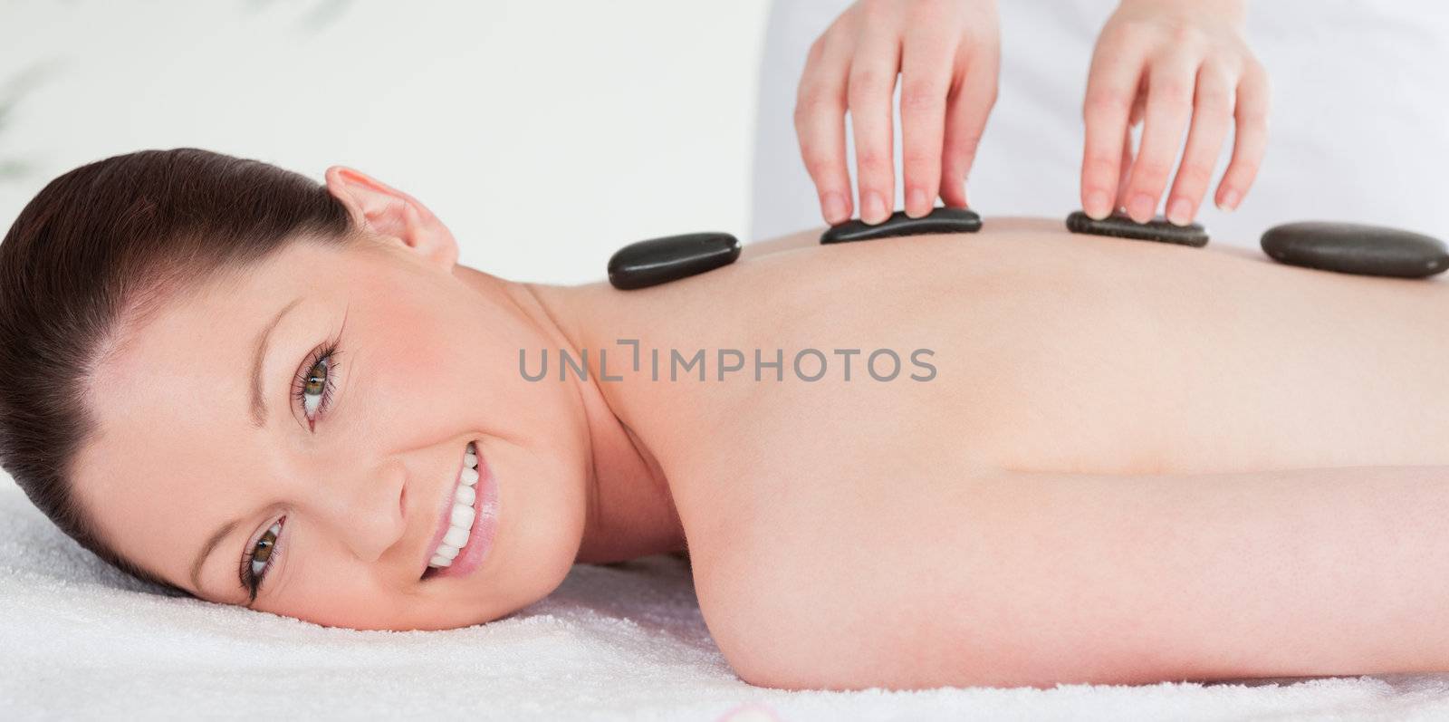 Smiling woman receiving a hot stone massage by Wavebreakmedia