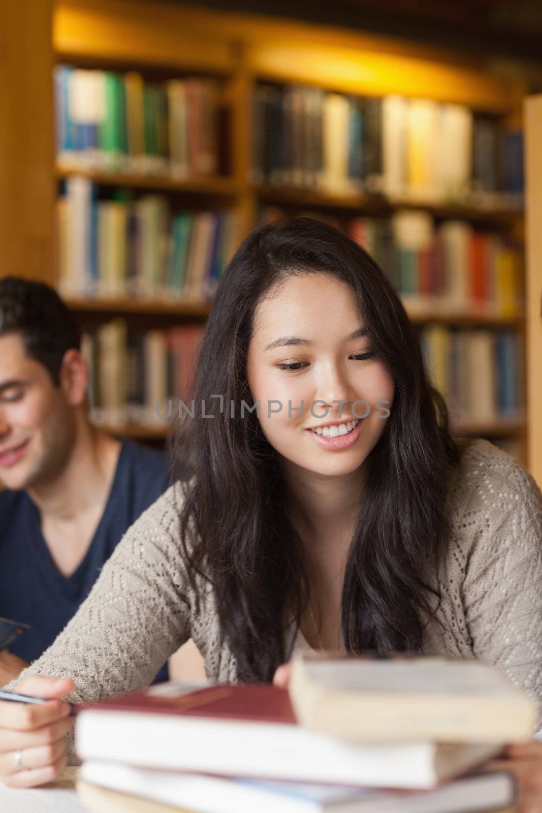 Student sitting at table smiling at the library