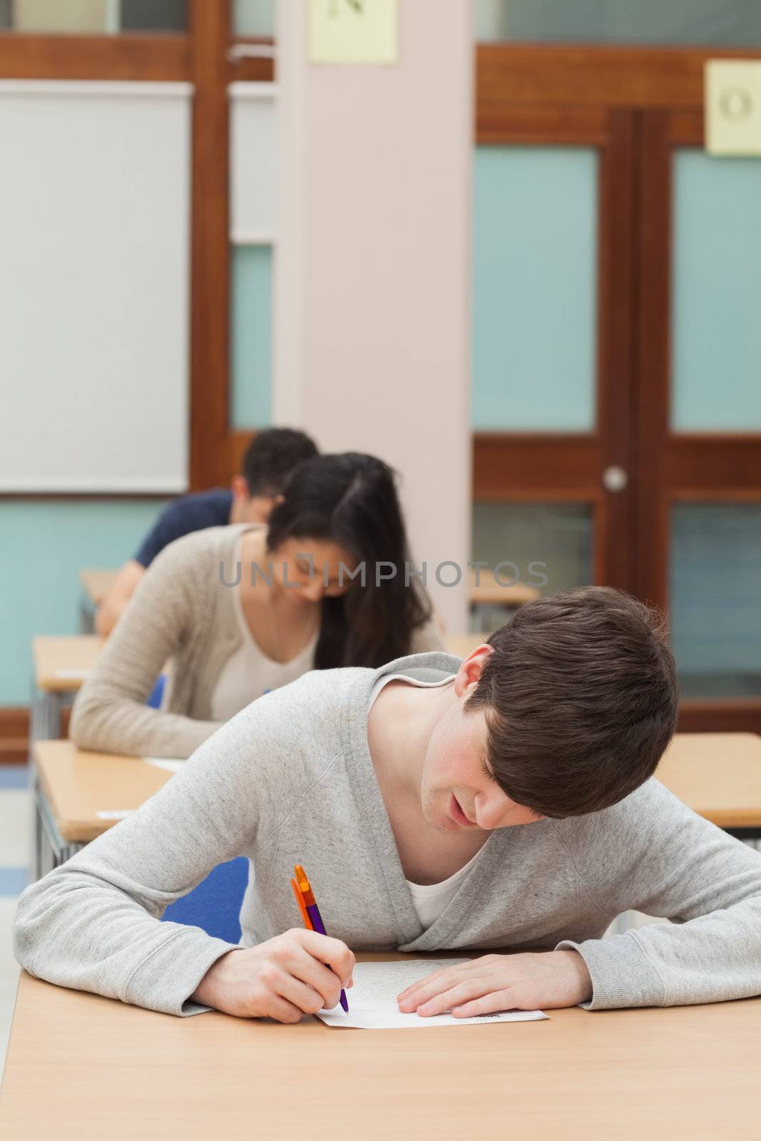 Man working hard on exam paper in exam hall 