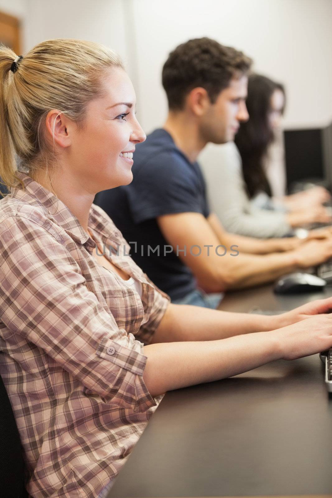 Woman sitting typing and smiling at computer class