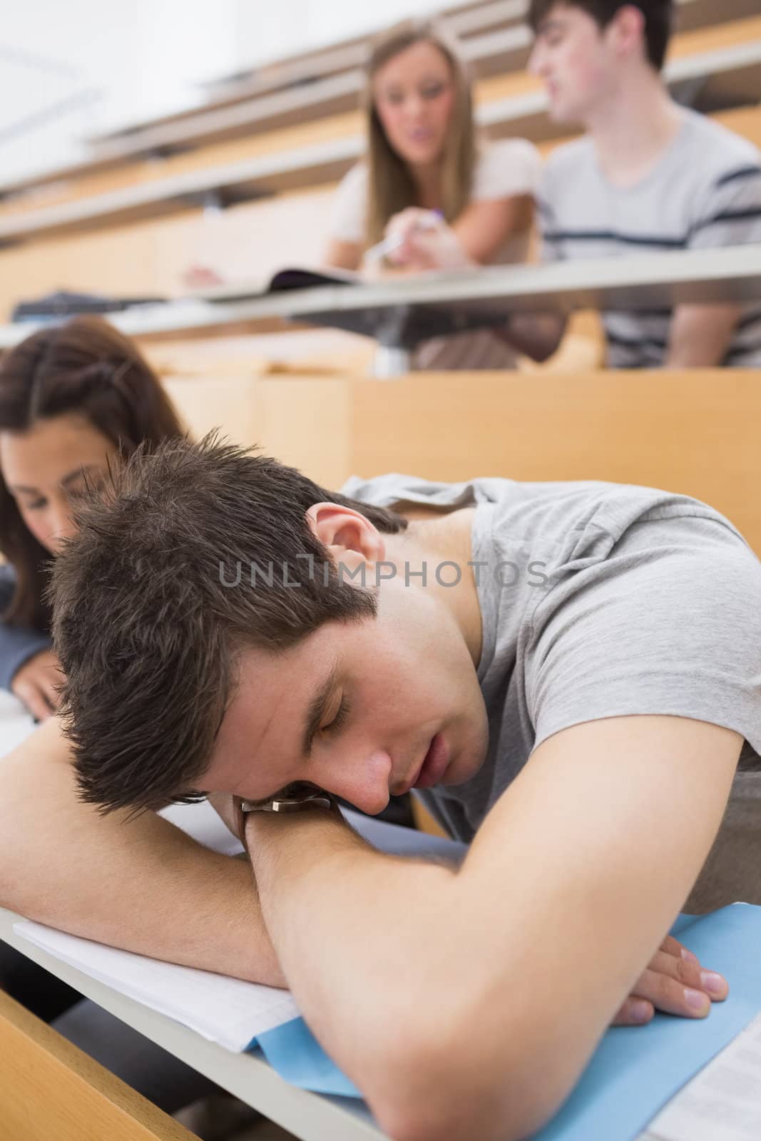 Student sleeping at the lecture hall leaning on table