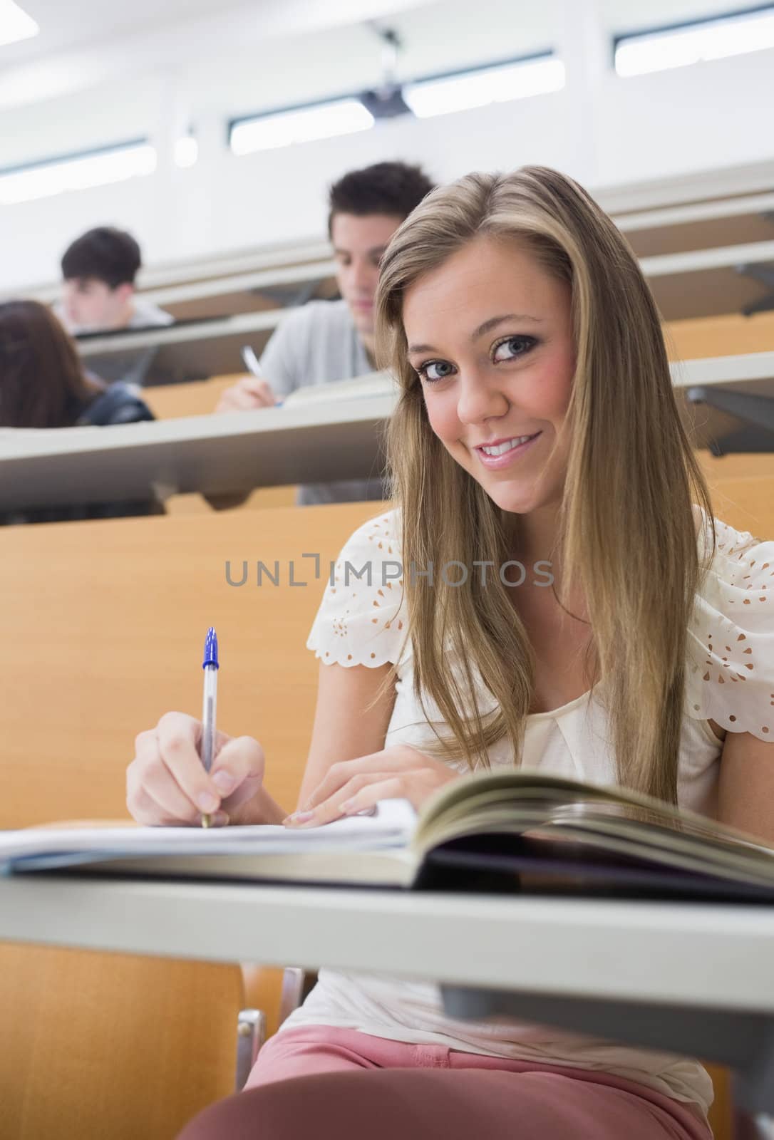 Woman sitting at the lecture hall making notes by Wavebreakmedia