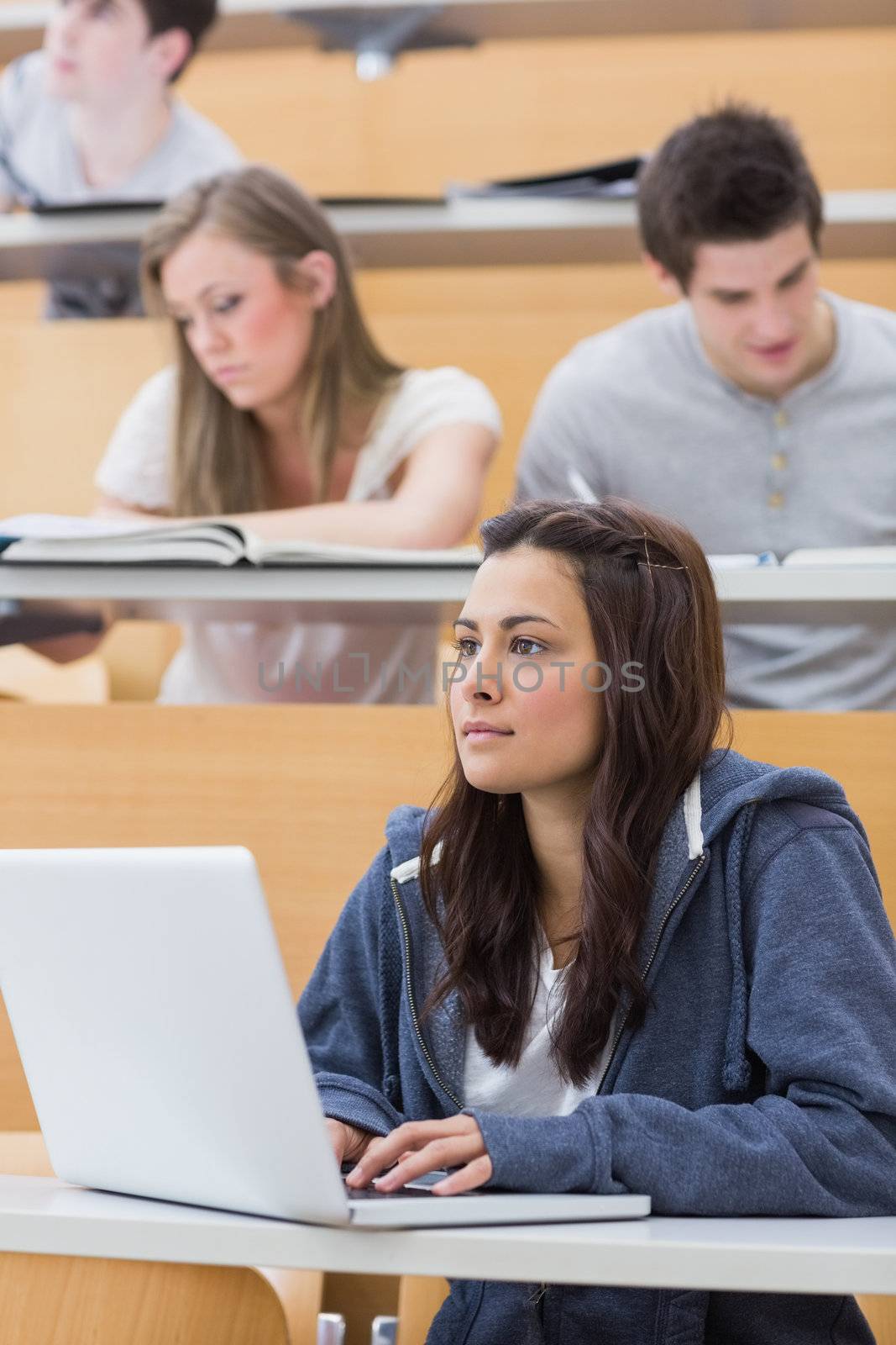 Concentrated girl sitting at the lecture hall with her laptop