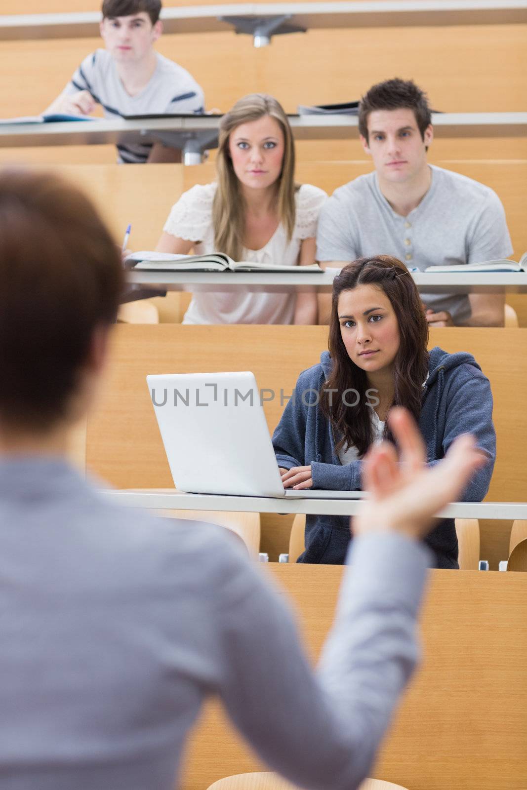 Students sitting at the lecture hall listening by Wavebreakmedia