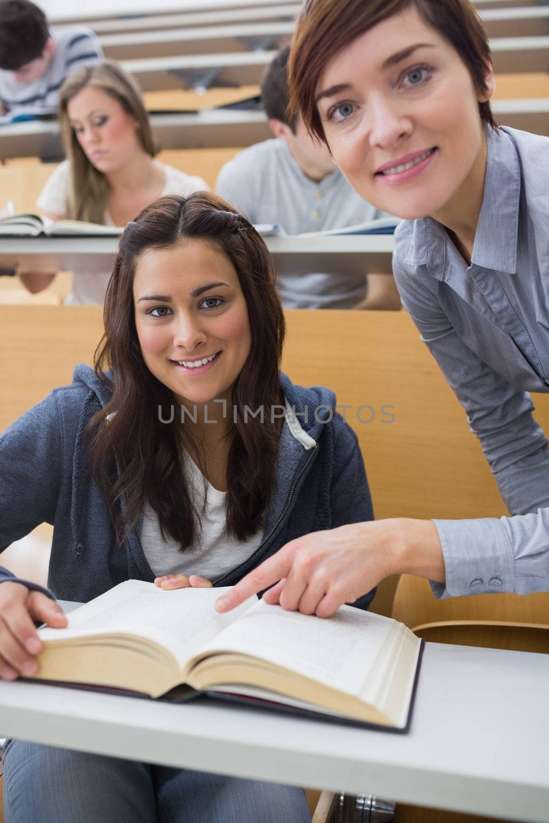 Smiling student and lecturer with book by Wavebreakmedia