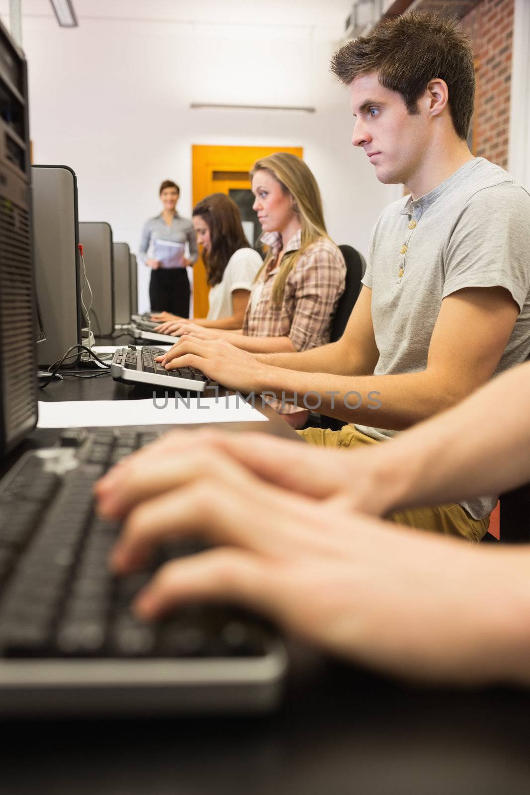 Man sitting at the computer while looking at the screen in college computer class