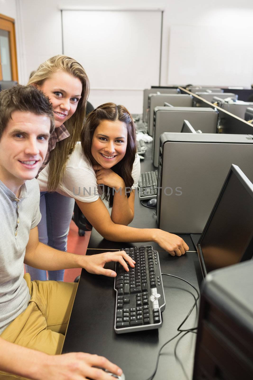 Students sitting at the computer room smiling  by Wavebreakmedia