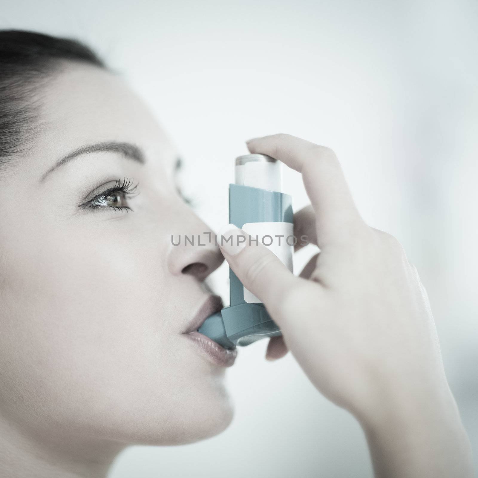 Woman using an asthma inhaler as prevention