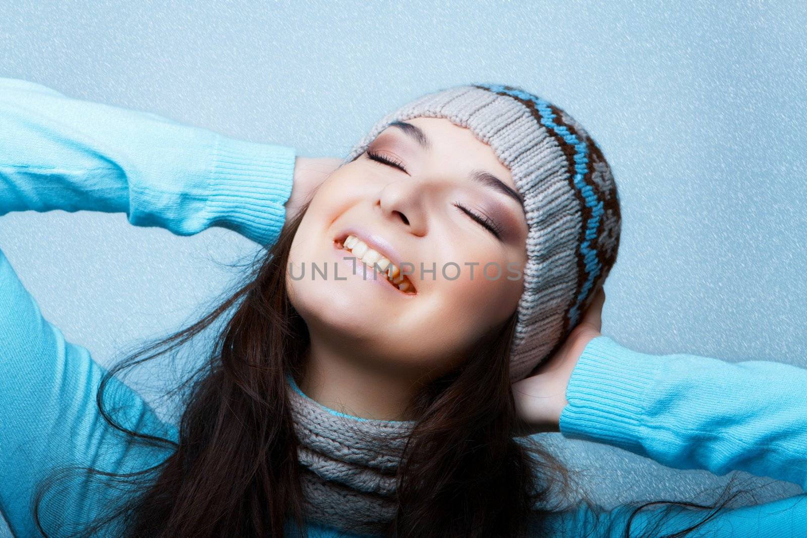 happy woman in blue snowy background in the cap