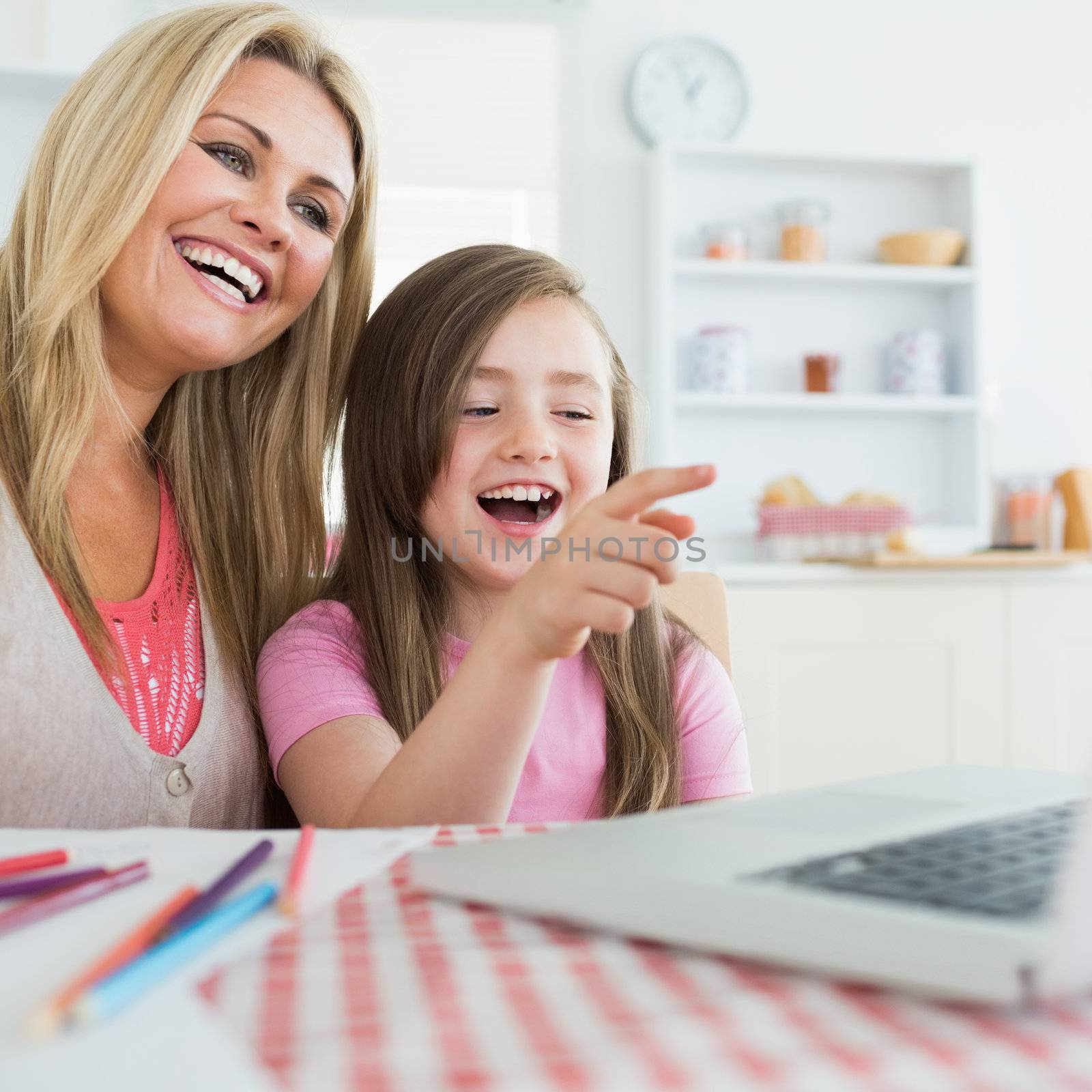 Mother and daughter laughing at laptop by Wavebreakmedia
