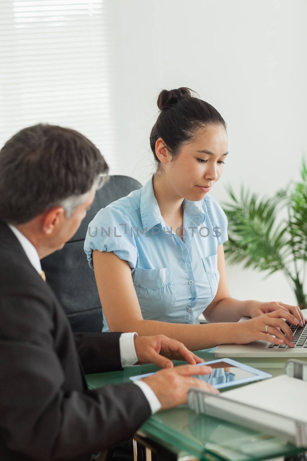 Two business people working hard on laptop and digital tablet in an office