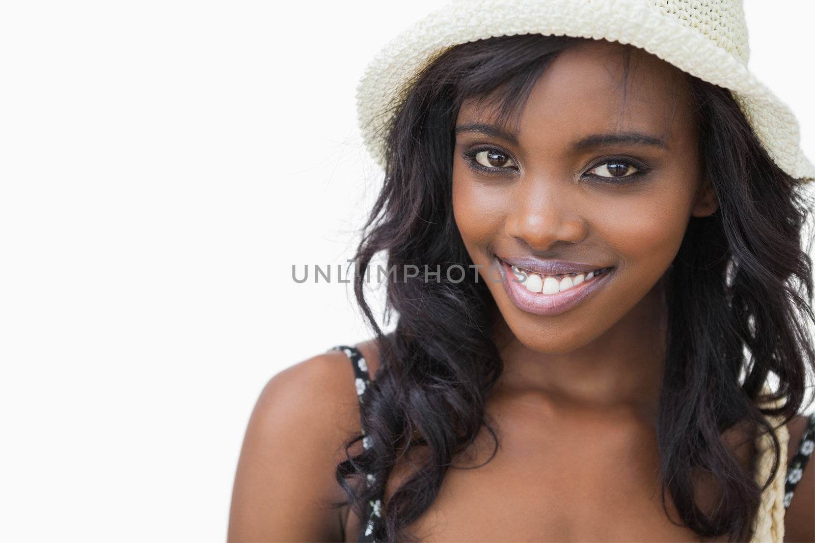 Woman wearing summer hat while smiling against white background