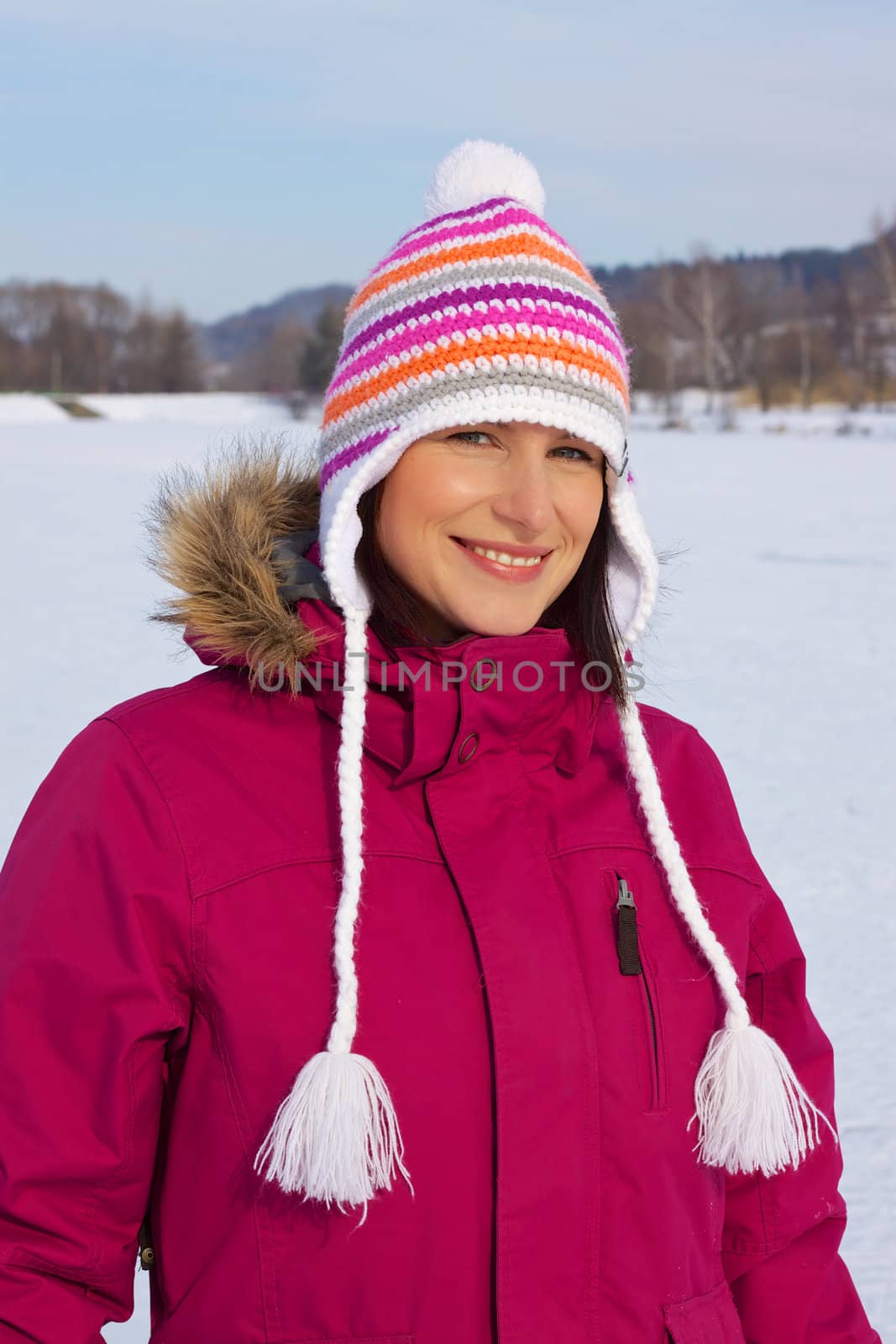 Smiling young woman wearing knitted winter cap with natural winter background