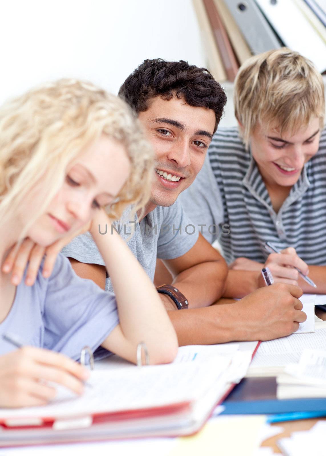 Teen guy studying in the library with more friends