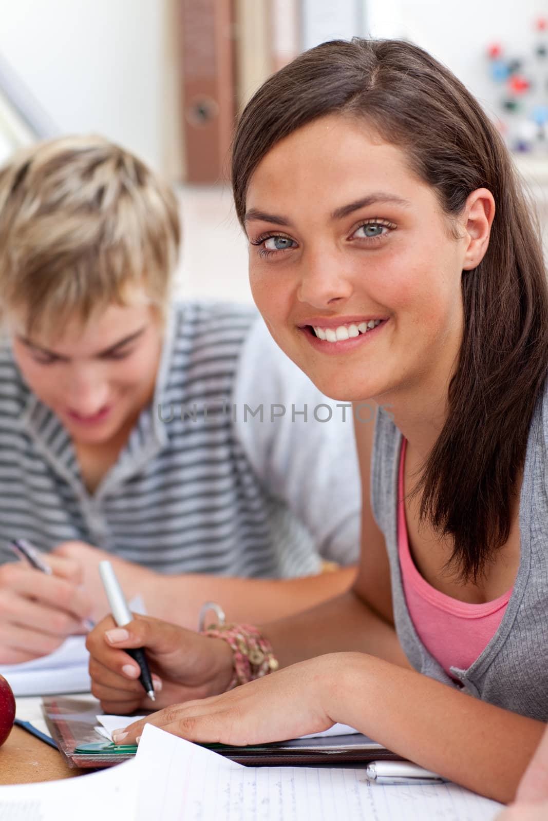 Smiling teen girl studying in the library with her friends by Wavebreakmedia