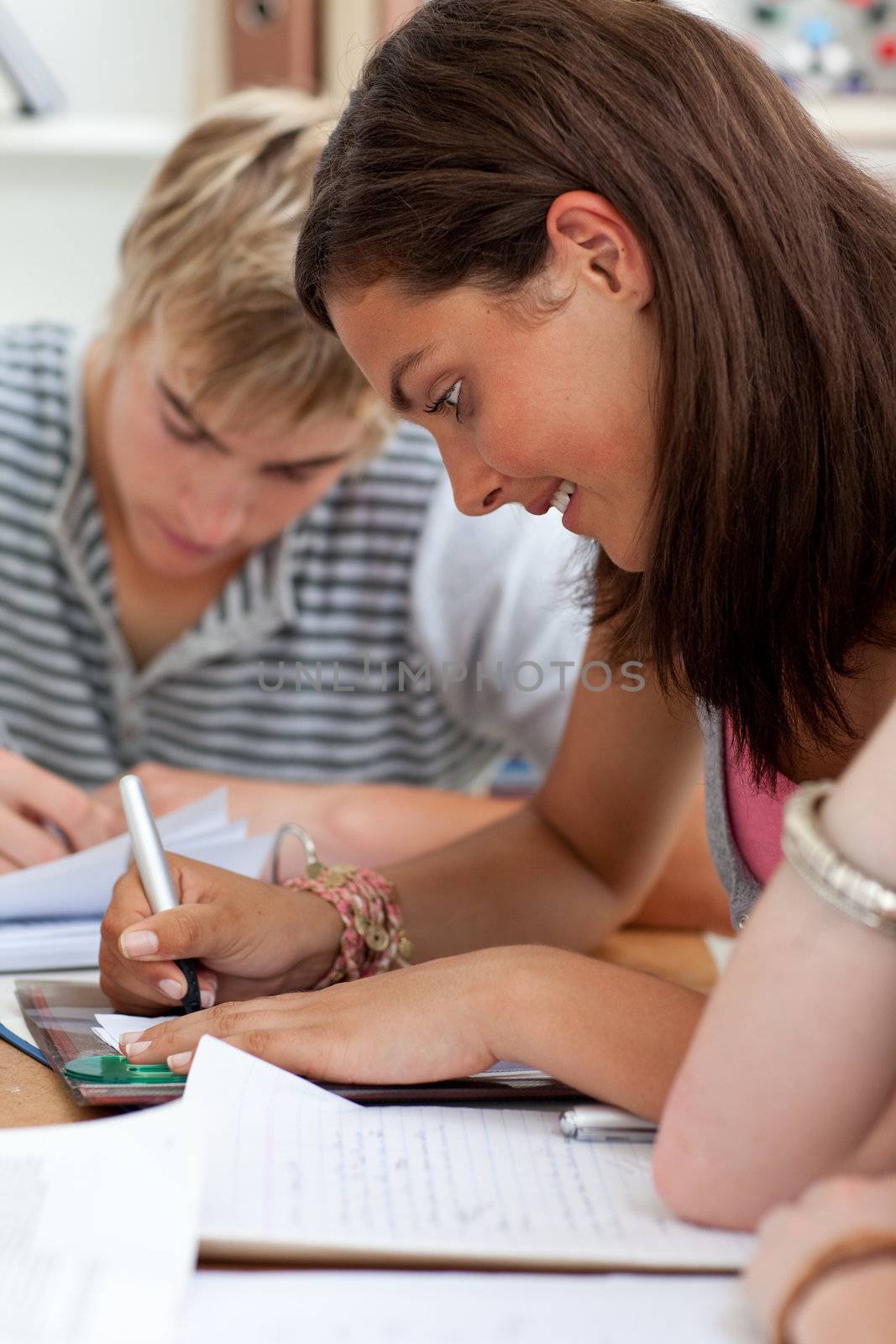 Teen girl studying in the library with her friends by Wavebreakmedia