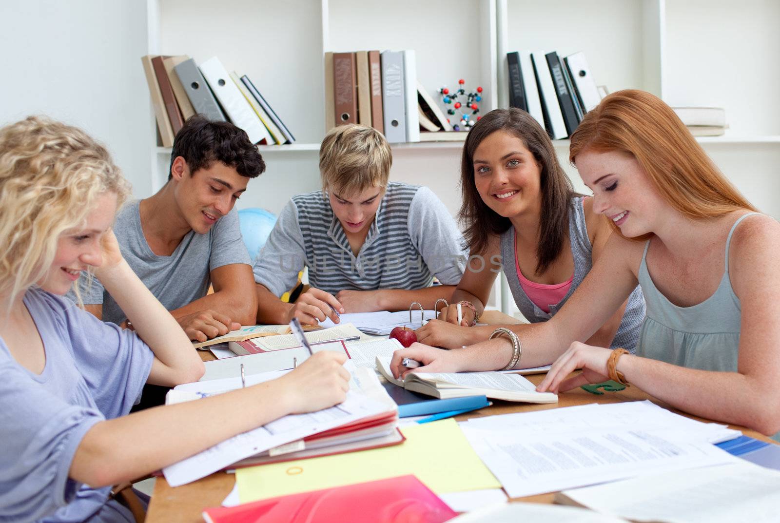 Smiling teenagers studying in the library. Concept of education