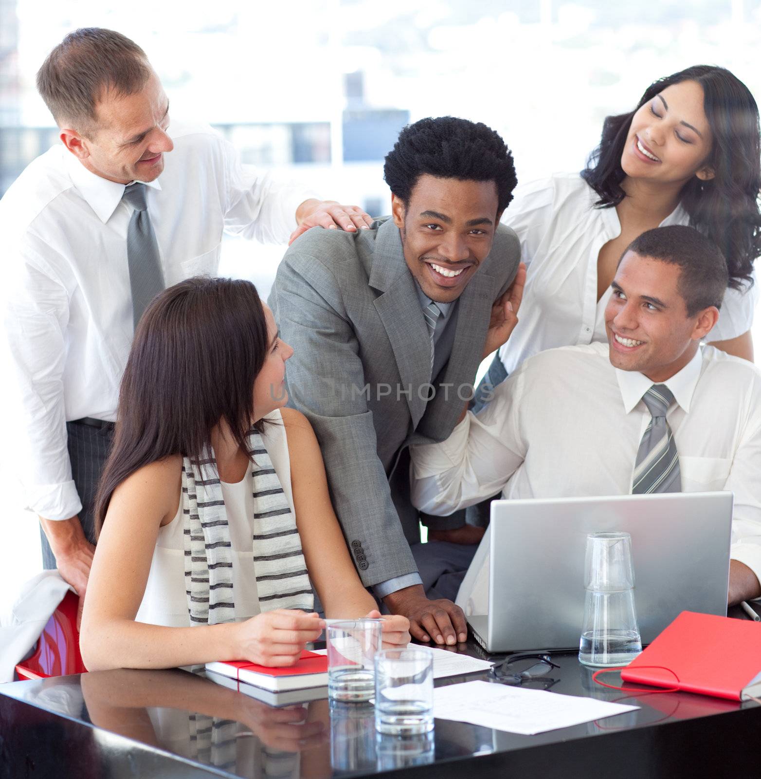 Smiling multi-ethnic business team working with a laptop in office